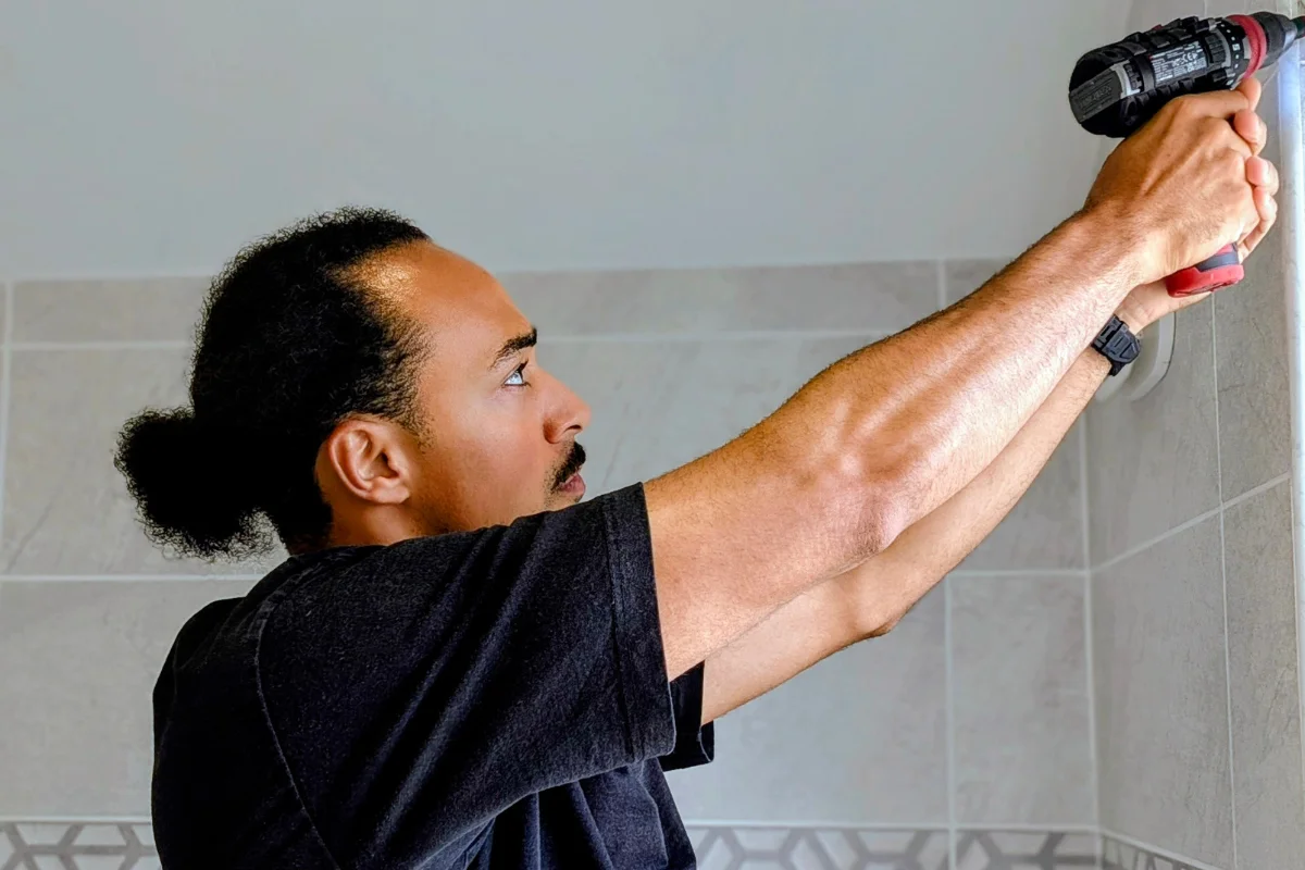 Bradley from Lord Knows How drilling to mount a fixture in a tiled bathroom